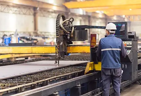 Factory worker operating an industrial CNC cutting machine secured with equipment financing
