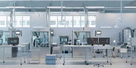 Interior of a state-of-the-art pharmaceutical production plant with sterile cleanroom, advanced medical assembly machinery, and laboratory monitoring stations.