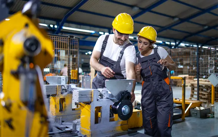 Industrial employees collaborate with complex equipment and robots to boost factory efficiency.